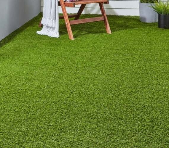 10mm (Oman) artificial grass installed on a clean, modern patio with wooden furniture.